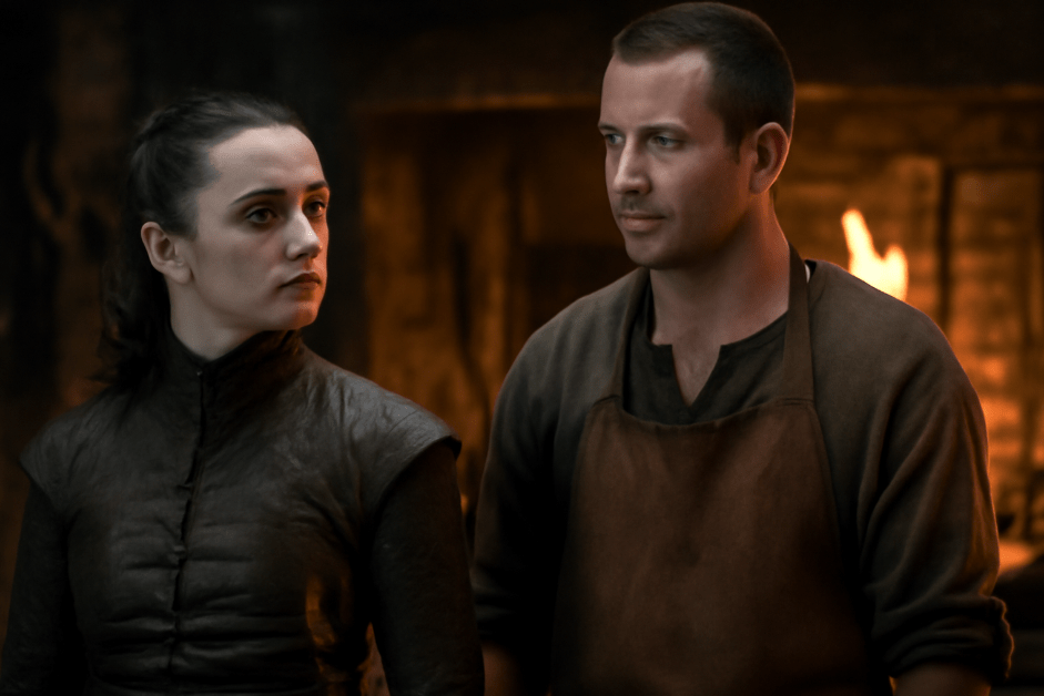 Arya Stark and Gendry standing side by side in a dimly lit forge, with Arya having a fierce yet thoughtful expression and Gendry looking humble and strong. Their bond is highlighted by the warm firelight and the shadows in the background, symbolizing their deep respect and connection.