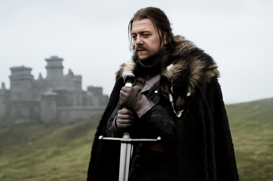 Ned Stark standing solemnly with his sword 'Ice' in hand, gazing over Winterfell, symbolizing his sense of honor and the tragic weight of his decisions.