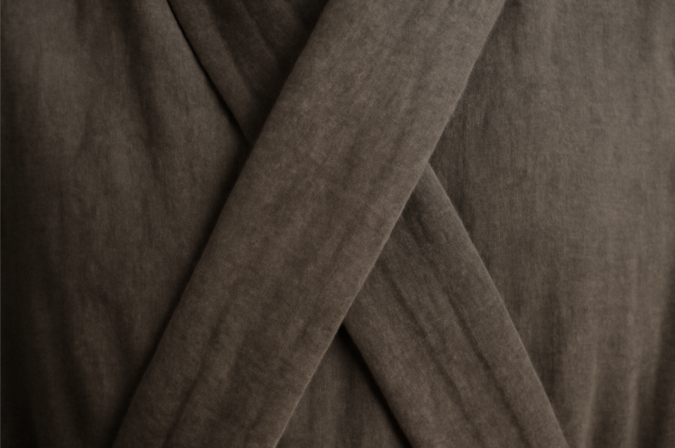 "Close-up of Lord Varys's neutral-toned robes, showcasing the subtle elegance of high-quality fabric in shades of gray and brown. The textured, overlapping layers of the robe emphasize its simple yet refined design, evoking a sense of strategic restraint and quiet power without any ornate detailing or embellishments." 