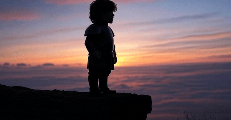 Silhouette of Tyrion Lannister standing confidently on a cliff, gazing at a vibrant sunrise over a grand horizon, symbolizing empowerment and a bright future
